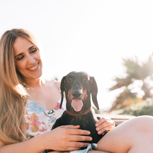 Free photo smiling woman looking at her cute pet dog sticking out tongue