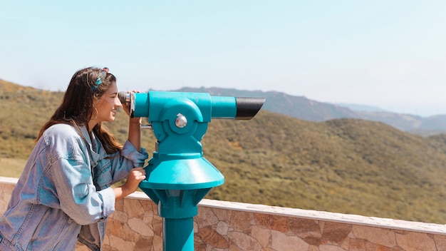 Smiling woman looking through spyglass