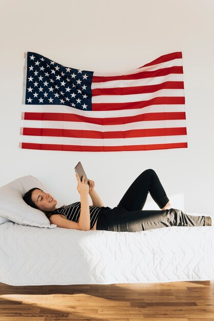 Smiling woman lying on bed and using tablet