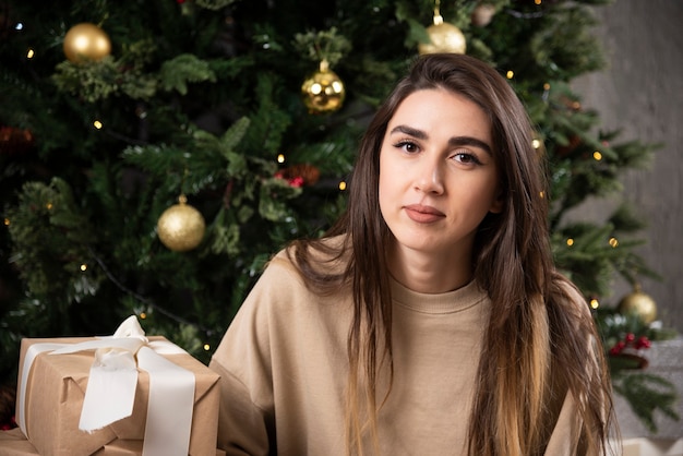 クリスマスプレゼントとふわふわのカーペットの上に横たわっている笑顔の女性。