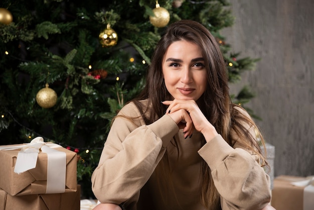 Smiling woman lying down on fluffy carpet with Christmas presents .