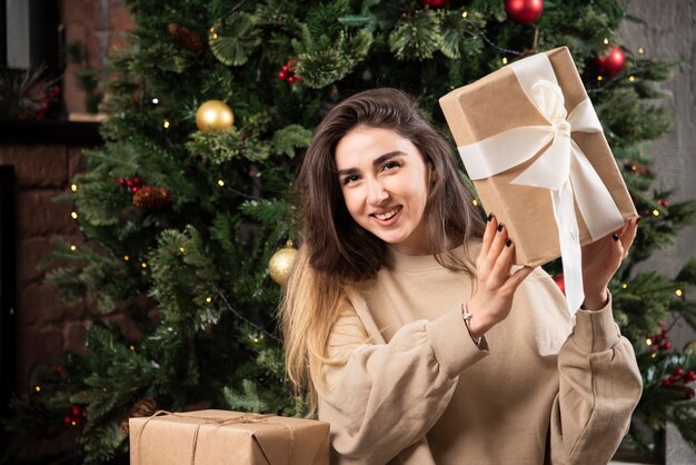 Smiling woman lying down on fluffy carpet with Christmas presents .