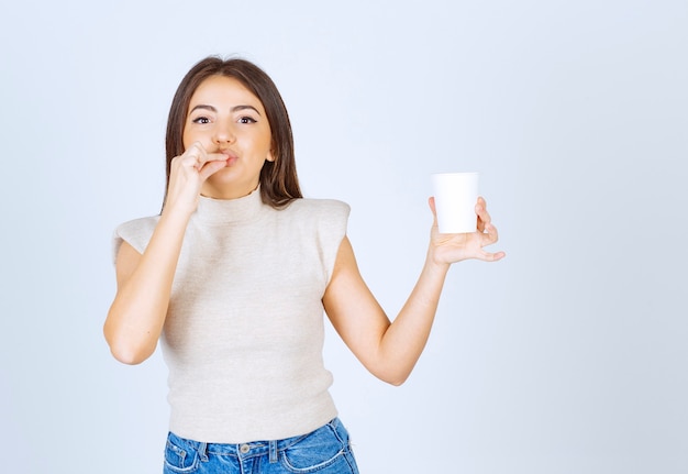 A smiling woman model showing a plastic cup and posing.