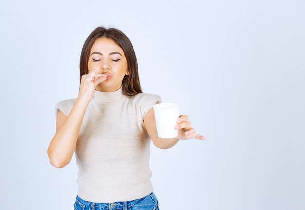 プラスチック製のコップを見せてポーズをとる笑顔の女性モデル。