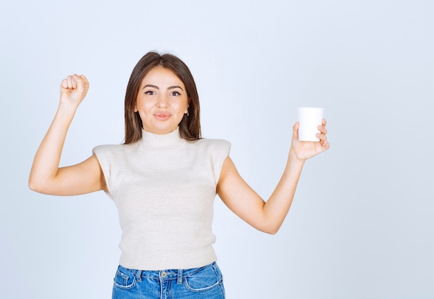 プラスチック製のコップを見せてポーズをとる笑顔の女性モデル。