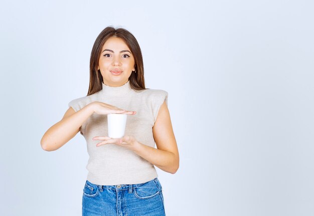 A smiling woman model showing a plastic cup and posing.