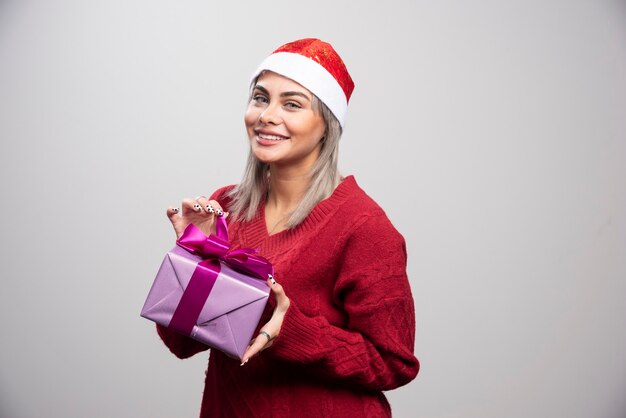 보라색 선물 상자와 함께 서 있는 웃는 여자 모델