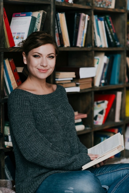 Smiling woman near bookshelf looking at camera