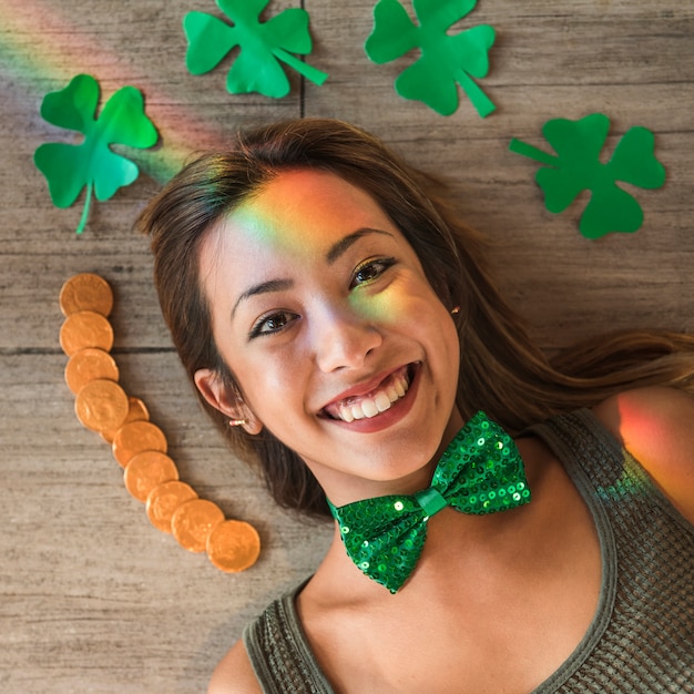 Free photo smiling woman near heap of coins and paper clovers on floor