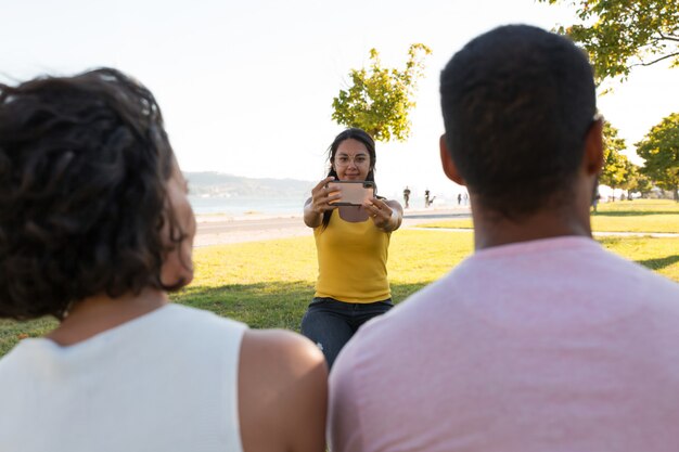 Smiling woman photographing friends in park