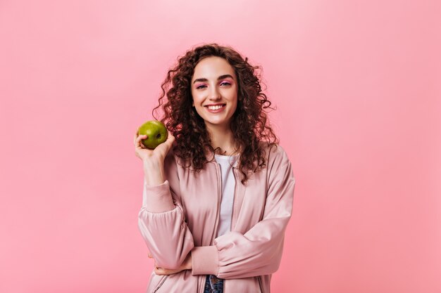 Smiling woman in pink outfit holding fresh Apple