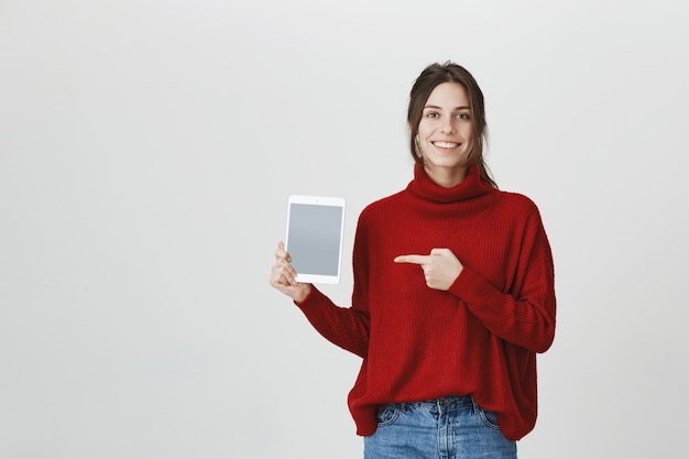 Smiling woman pointing at digital tablet screen