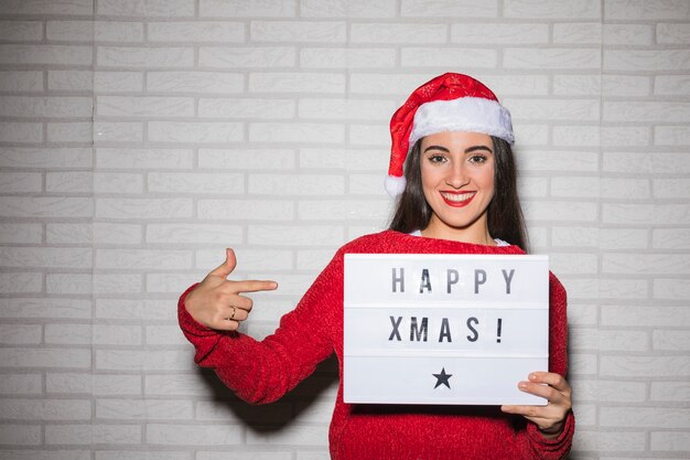 Улыбающаяся женщина, указывая на знак Счастливый Рождество