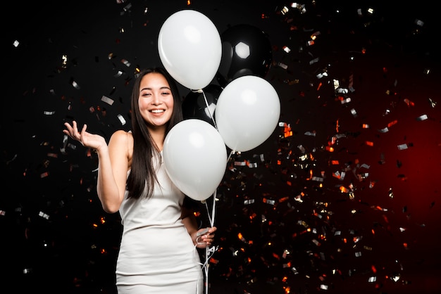Улыбается женщина позирует с воздушными шарами на новогодней вечеринке