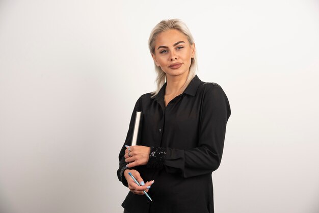 Smiling woman posing with a cup and clipboard on white background. High quality photo