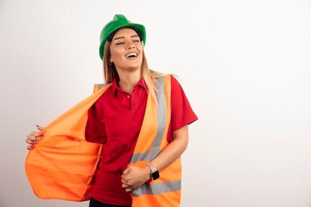 保護制服と白い背景の上のヘルメットのポーズで笑顔の女性。