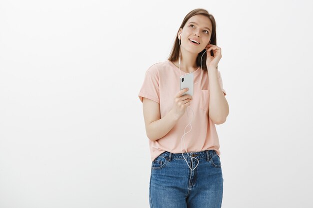 Улыбающаяся женщина положила наушники, чтобы слушать подкаст в приложении для мобильного телефона