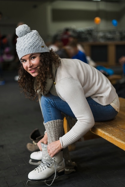 Foto gratuita donna sorridente che mette sui pattini da ghiaccio