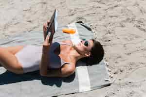 Free photo smiling woman reading book on beach