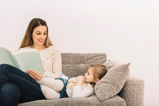 Smiling woman reading fairy tale to daughter