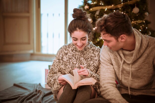 Smiling woman reading novel at boyfriend 