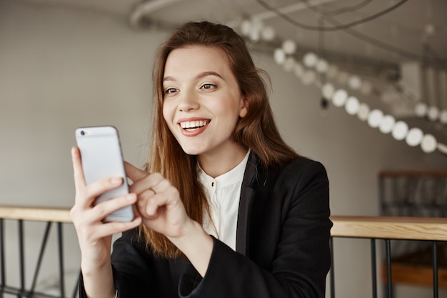 Smiling woman receive pleasant message, looking at mobile phone happy