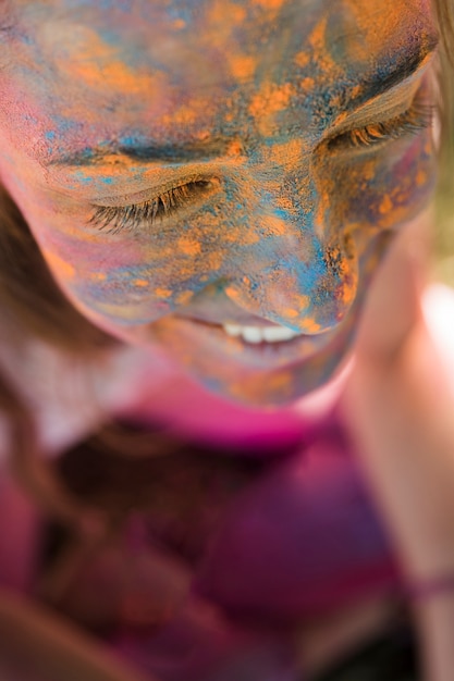 Smiling woman's face with blue and yellow holi powder