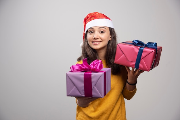 Smiling woman in Santa hat holding in hands Christmas presents . 