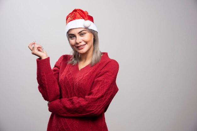 회색 배경에 포즈를 취하는 산타 모자에 웃는 여자.