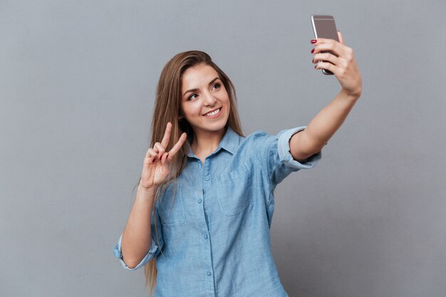 スマートフォンでselfieを作るシャツで笑顔の女性