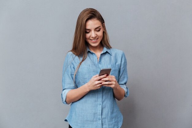 Улыбающаяся женщина в рубашке с помощью телефона