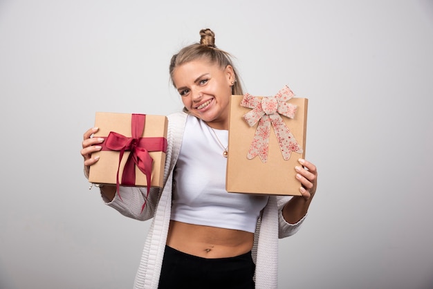 Smiling woman showing holiday gifts with happy expression.