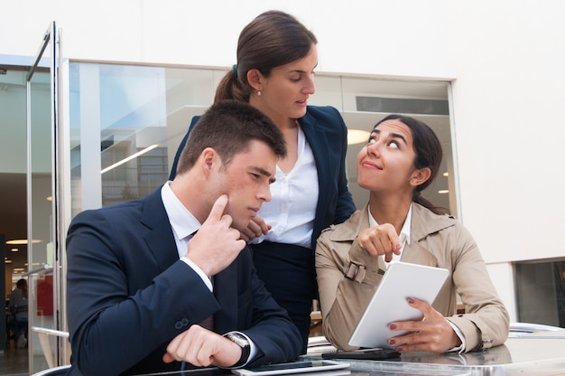 Smiling woman showing tablet screen to business people