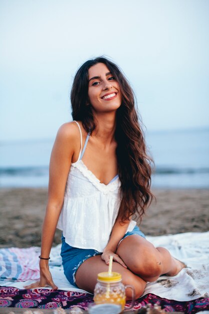 Улыбка женщины, сидящей на пляже