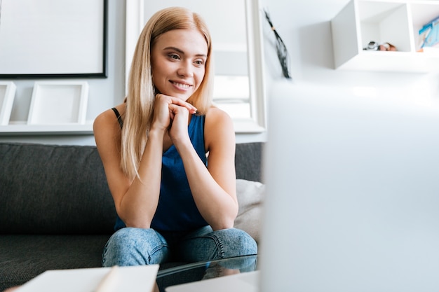 Smiling woman sitting on couch at home and thinking