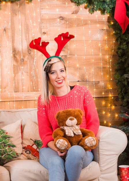 Smiling woman sitting on couch with teddy