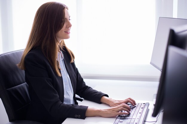 女性がコンピュータに入力して座って笑顔