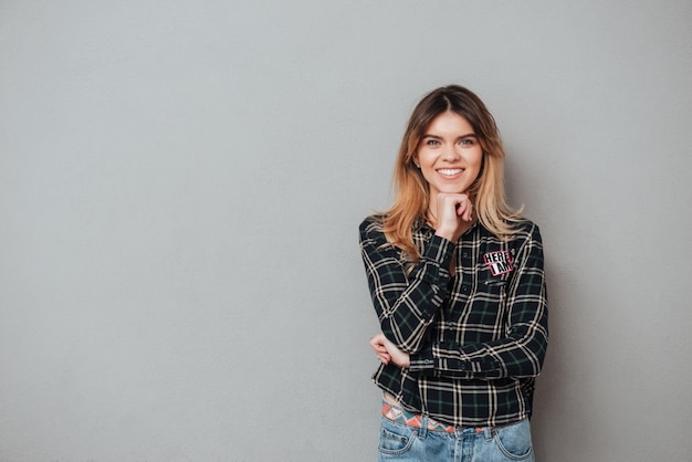 Smiling woman standing and holding hand at her chin