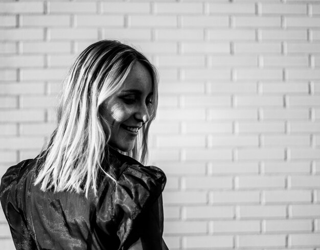 Smiling woman standing near brick wall