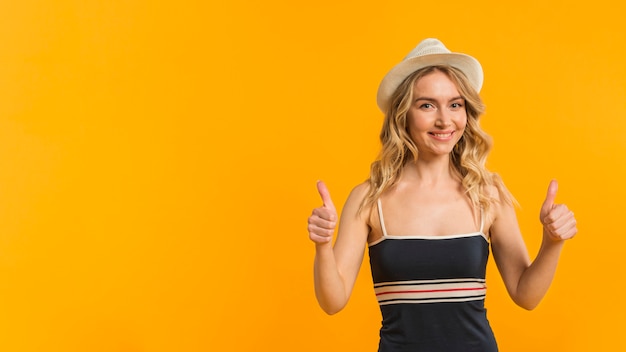 Smiling woman in summer clothes showing thumbs up