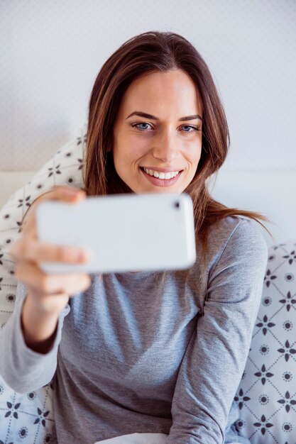 Smiling woman taking selfie in bed