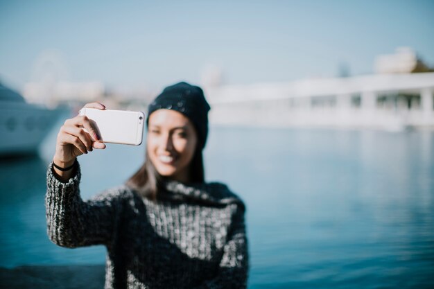 Smiling woman taking selfie with water in background