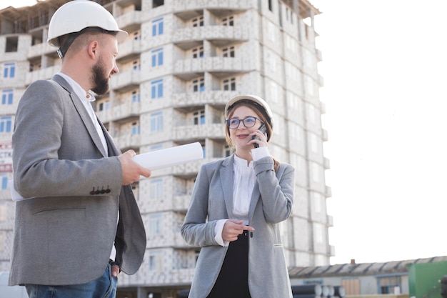 Free photo smiling woman talking on cellphone while her colleagues looking at each other