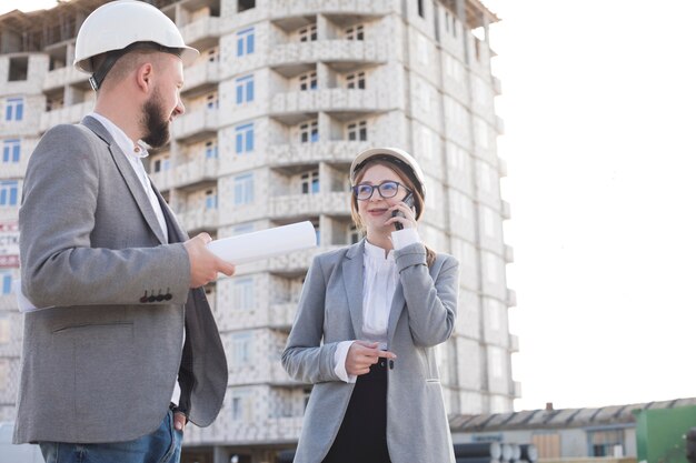 Smiling woman talking on cellphone while her colleagues looking at each other