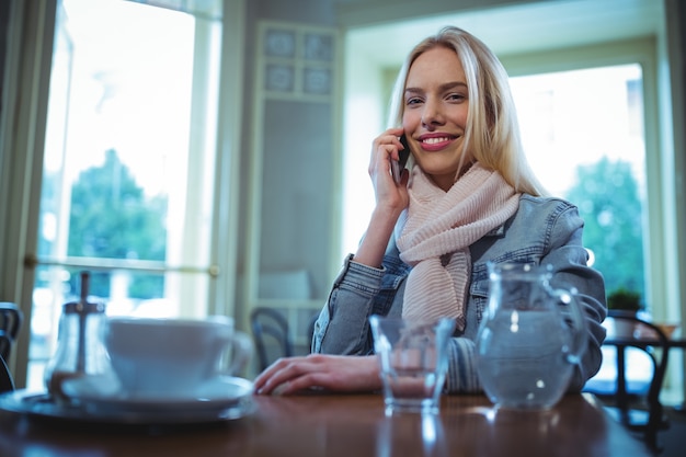 Smiling woman talking on mobile phone in cafÃ©