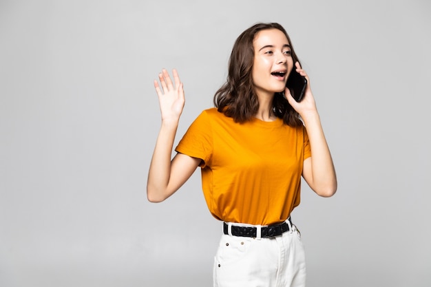 Donna sorridente che parla al telefono isolato su un muro grigio