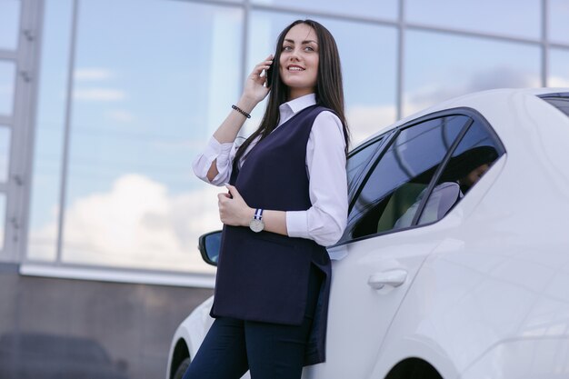 車に寄りかかって電話で話す笑顔の女性