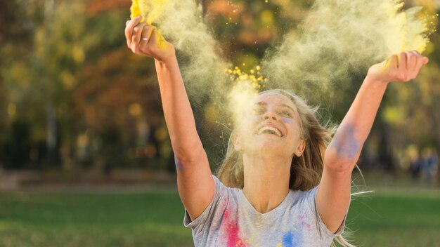 Smiling woman throwing color in the air