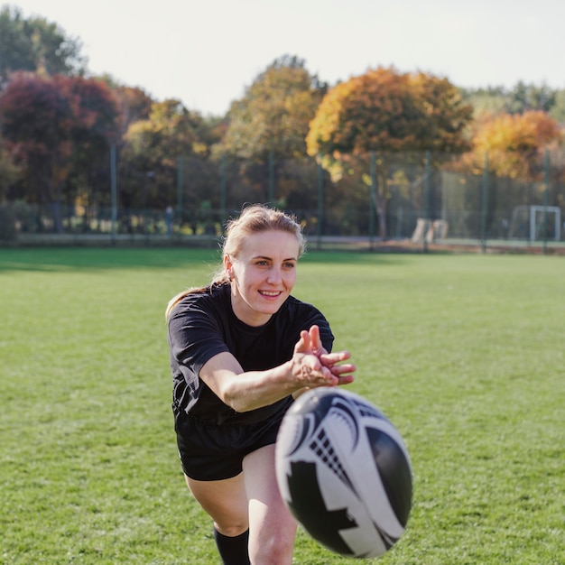 Foto gratuita donna sorridente che lancia una palla di rugby