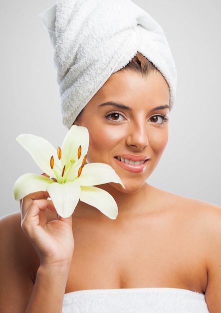 Smiling woman in towel holding lily